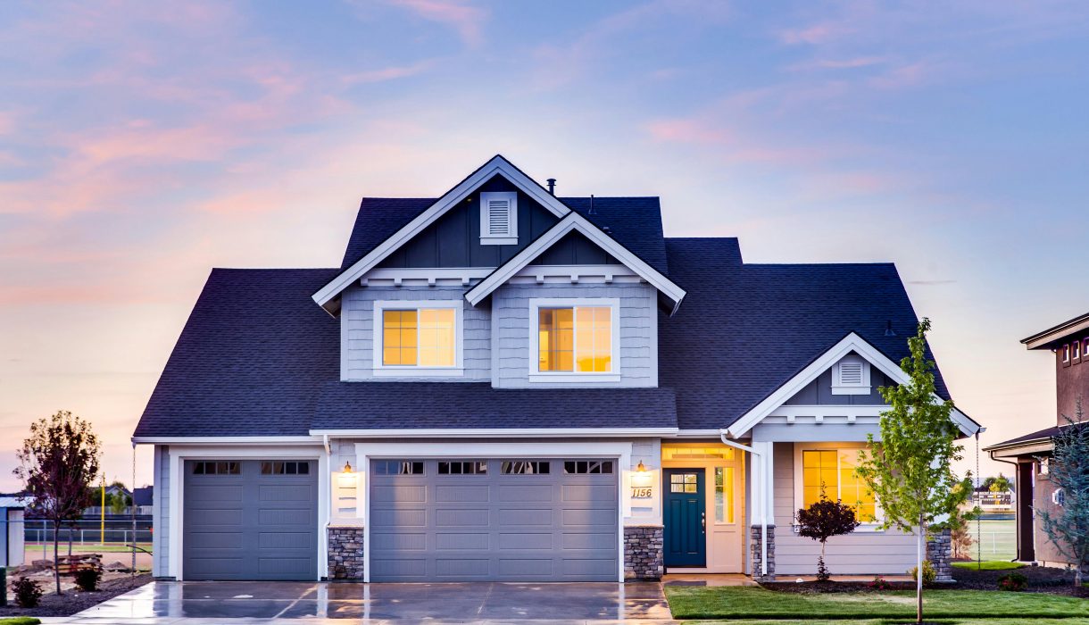 Beautiful two-story house with illuminated windows and garage at dusk.