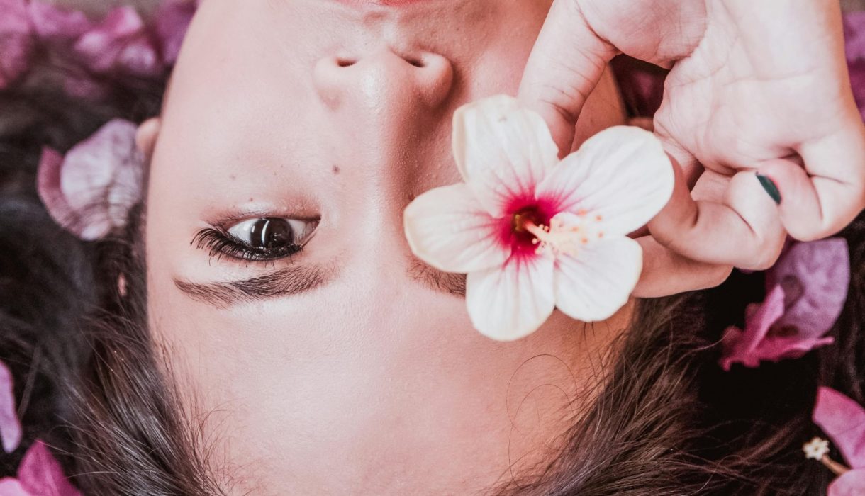 Elegant photoshoot featuring a woman holding a pink flower amidst petals.