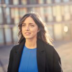 Portrait of a confident woman walking outdoors in an urban setting with a smile.